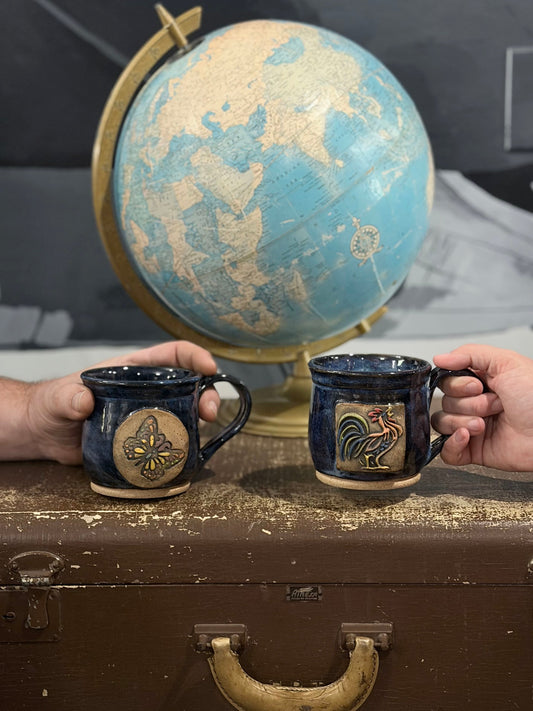 Two handmade coffee mugs with hands holding them with world globe in backgound